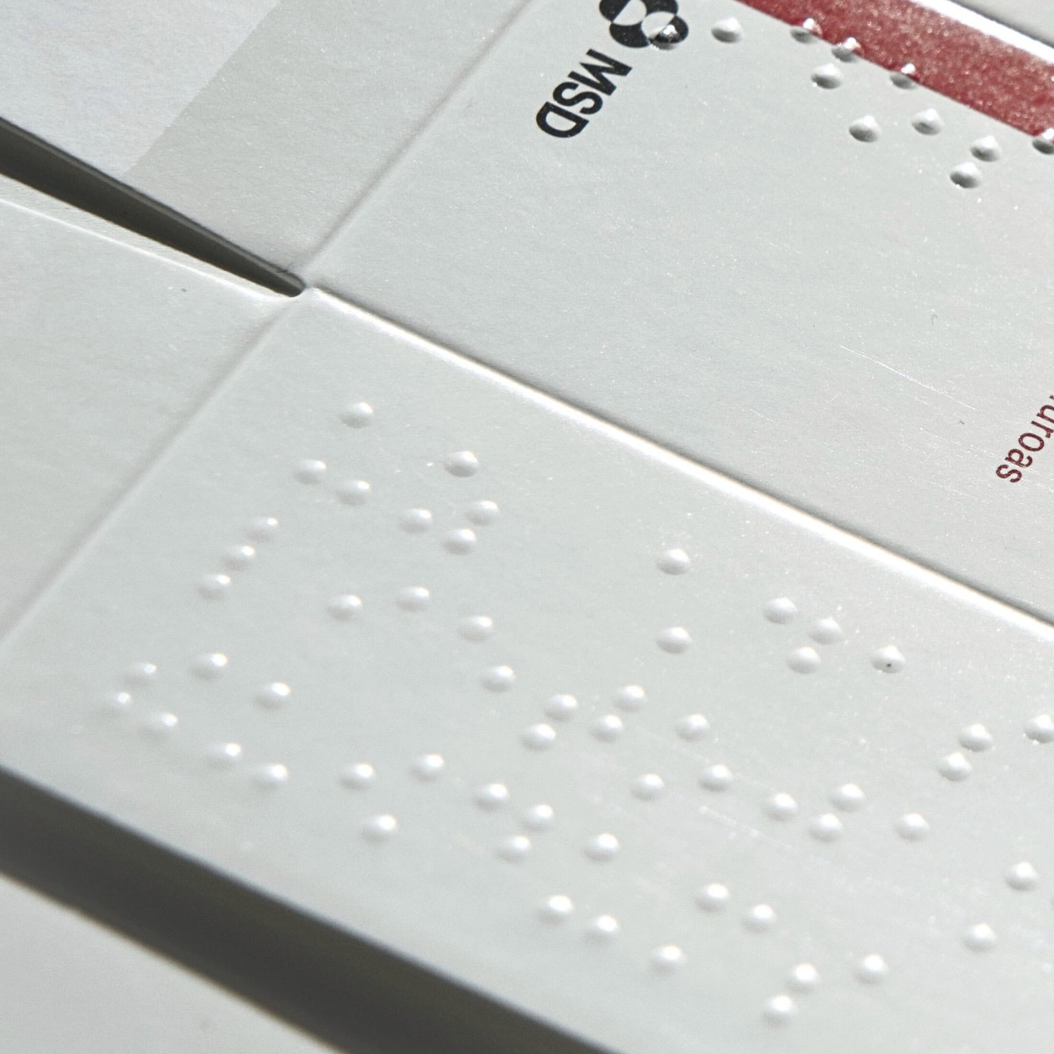 Image d'un emballage pharmaceutique avec des inscriptions en braille pour l'accessibilité des personnes malvoyantes.