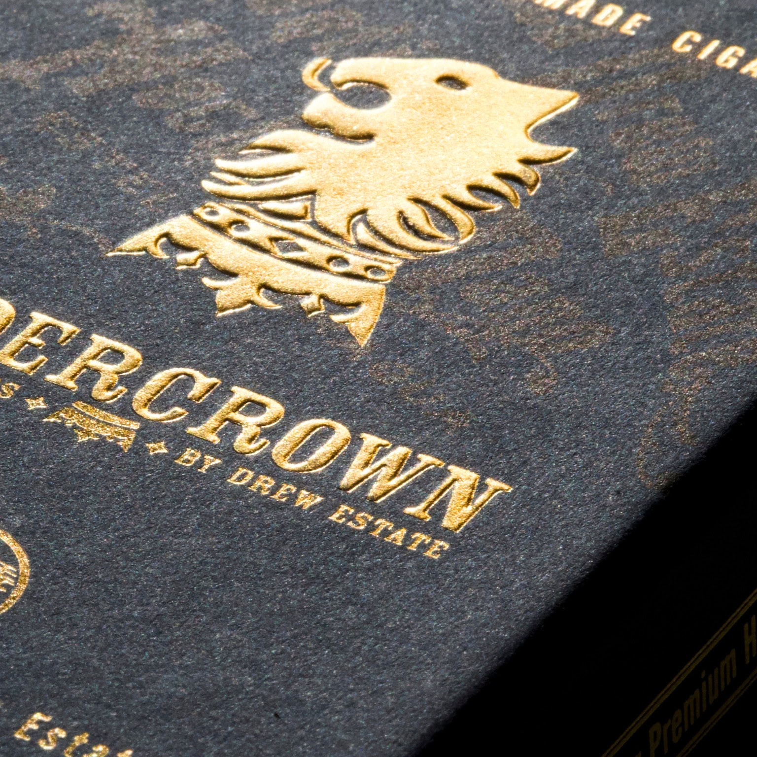 Image d'un emballage de cigares Undercrown par Drew Estate, avec un logo doré en relief représentant un lion couronné.