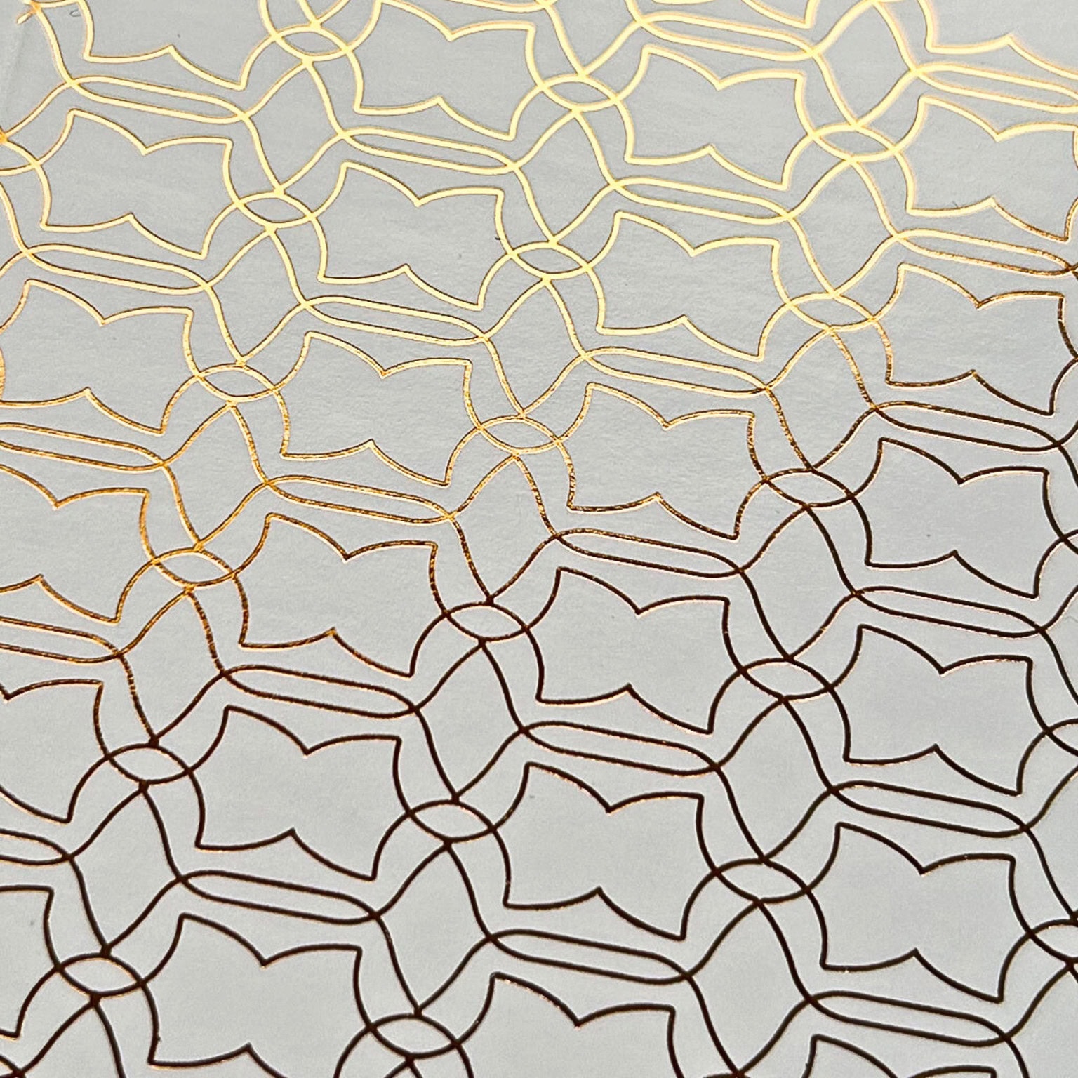 Image d'un motif géométrique complexe en dorure sur papier, illustrant la précision et l'élégance des techniques de finition.