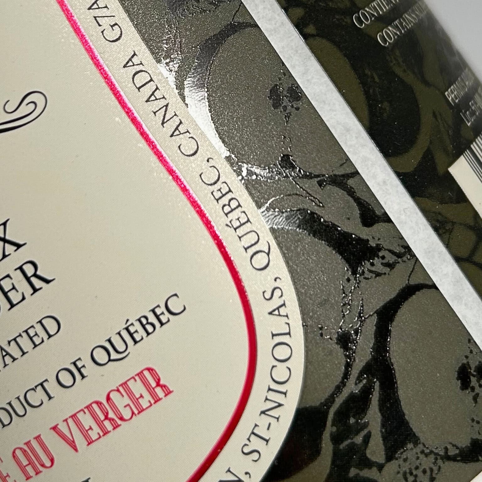 Image d'une étiquette de bouteille de cidre du Québec, avec des détails en relief et un texte indiquant l'origine du produit.