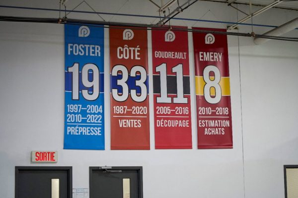 Bannières honorifiques des employés chez Produlith Image de bannières honorifiques affichées chez Produlith, mettant en avant les noms et années de service des employés Foster, Côté, Goudreault et Emery