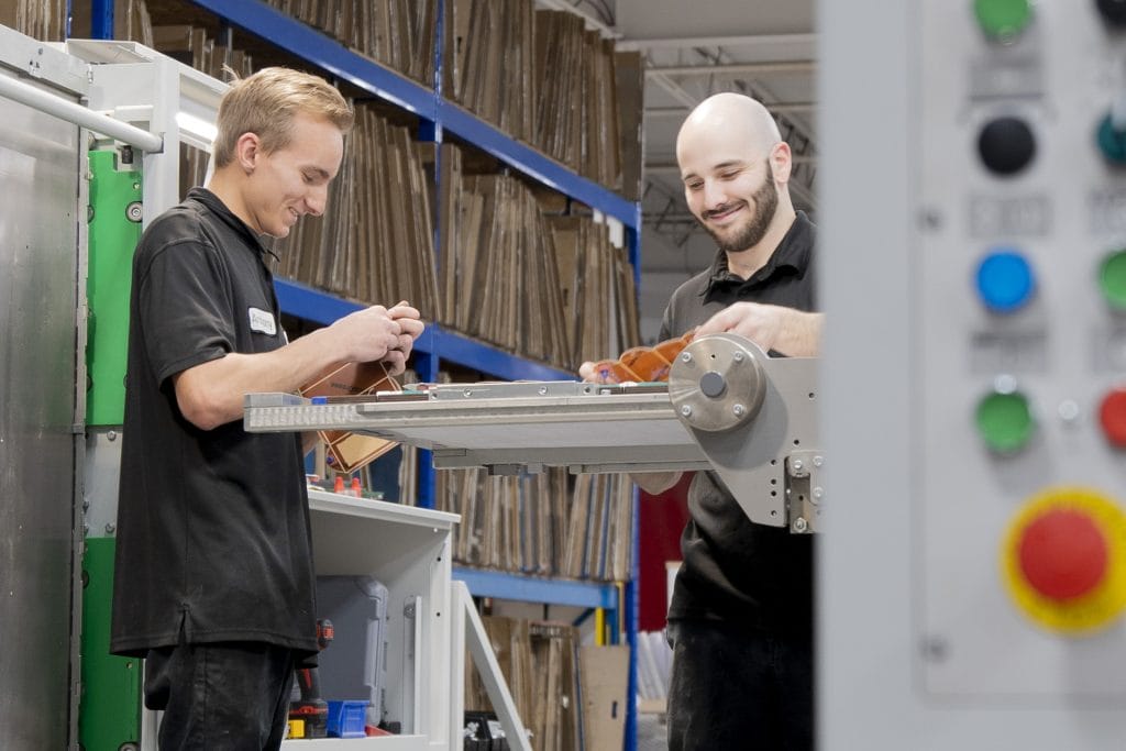 Image de deux employés de Produlith travaillant ensemble sur une ligne de production, manipulant des pièces avec précision et efficacité.