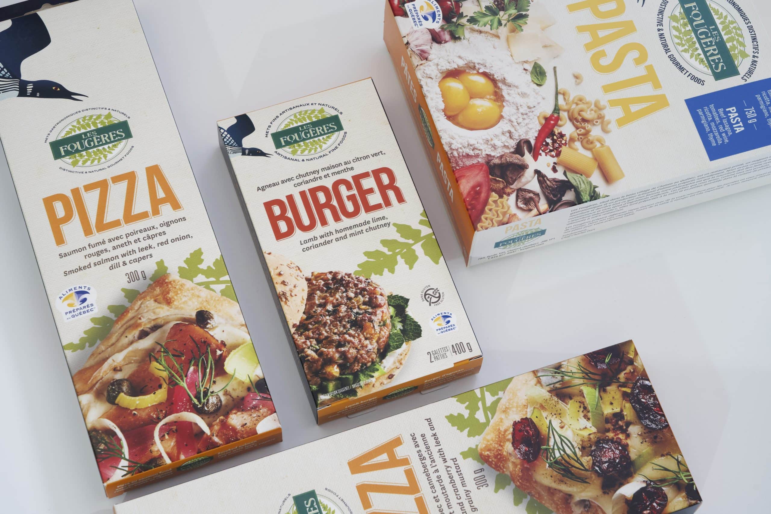 Packs of Les Fougères brand food products, including pizzas, burgers and pasta, laid out on a white surface.