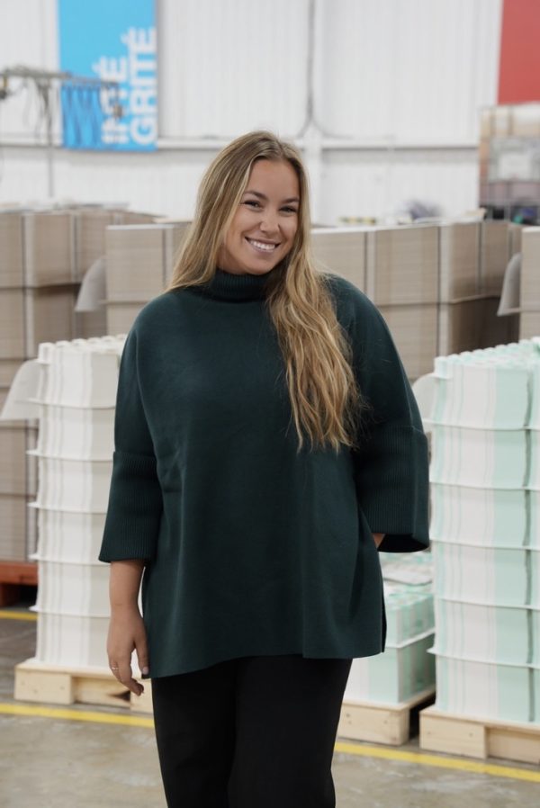 Megan Chartrand-Robichaud souriante dans un environnement industriel avec des matériaux de construct.