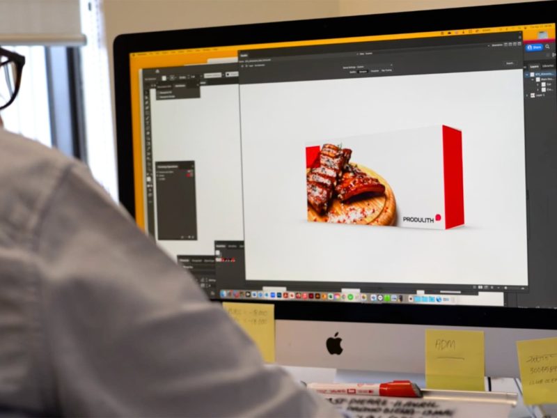 Image d'un graphiste travaillant sur un ordinateur, concevant l'emballage d'un produit alimentaire pour Produlith.